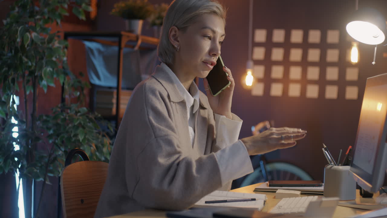 Kvinde taler i telefon ved sit skrivebord