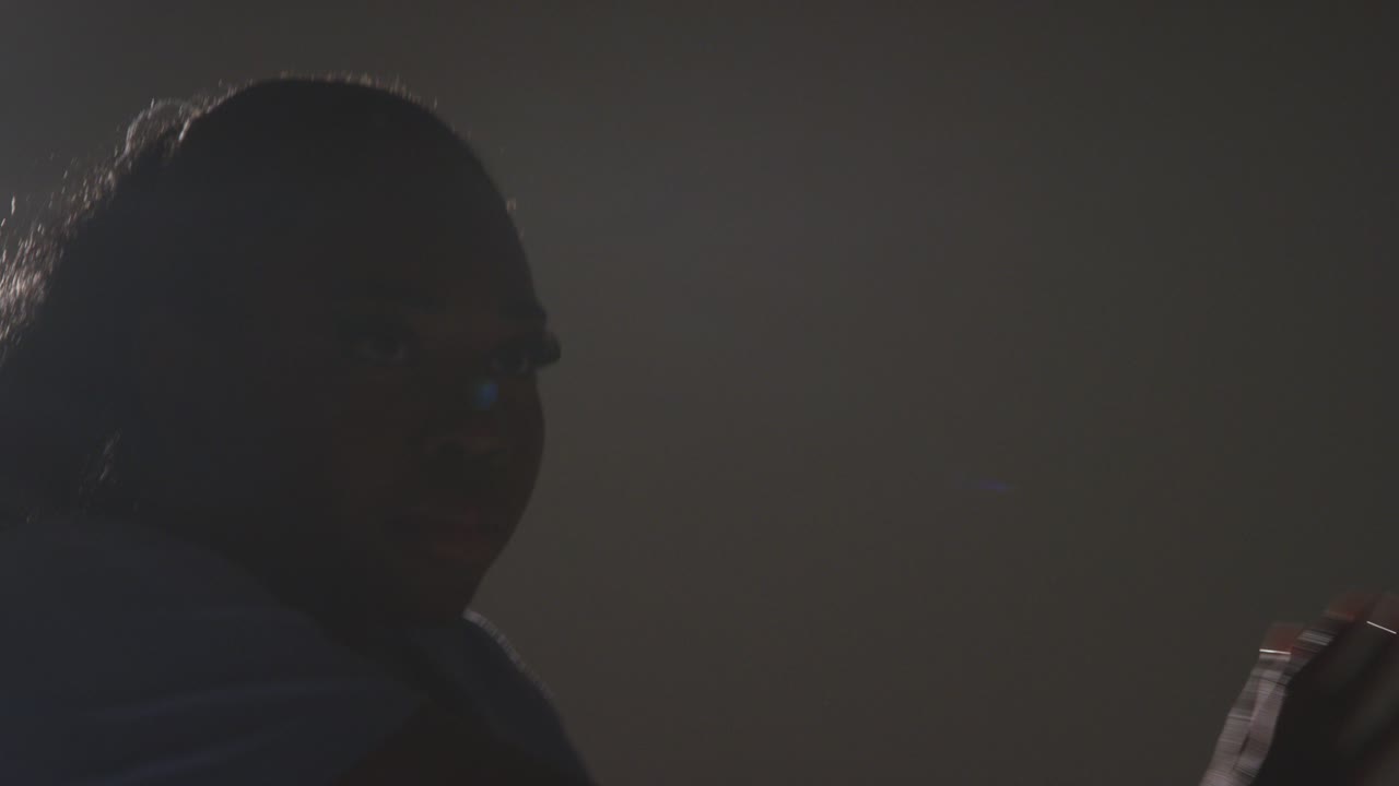 백라이트 된 머리와 어깨 스튜디오 초상화 촬영 젊은 여성 댄서가 스포트라이트에서 춤을 추고 있습니다.