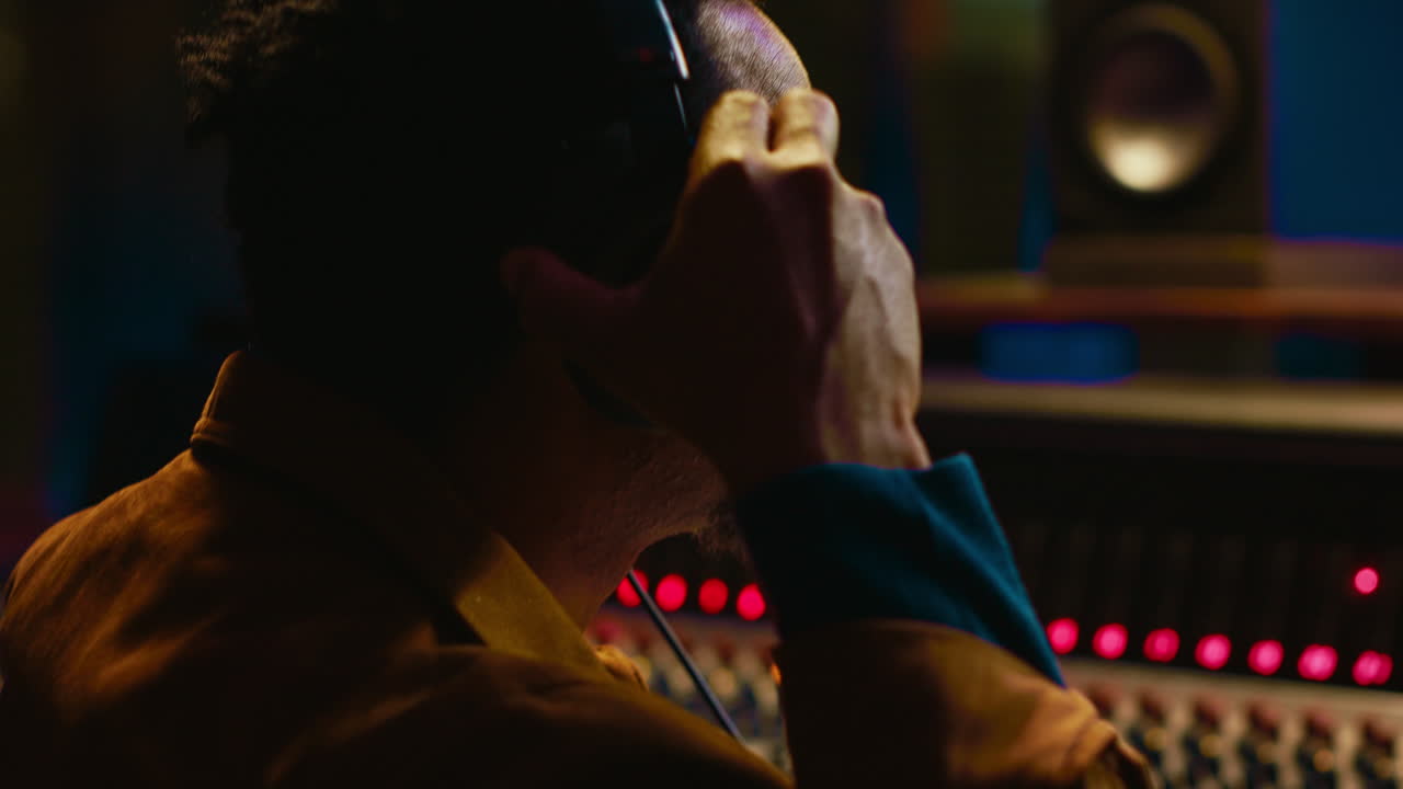 ingeniero de sonido afroamericano usando auriculares para escuchar grabaciones de audio