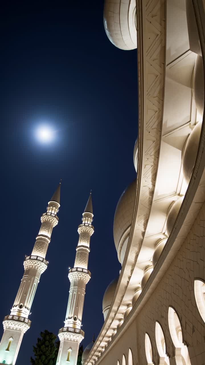 Una drammatica inquadratura dal basso mostra i minareti illuminati di una moschea sotto un cielo illuminato dalla luna, perfetto.