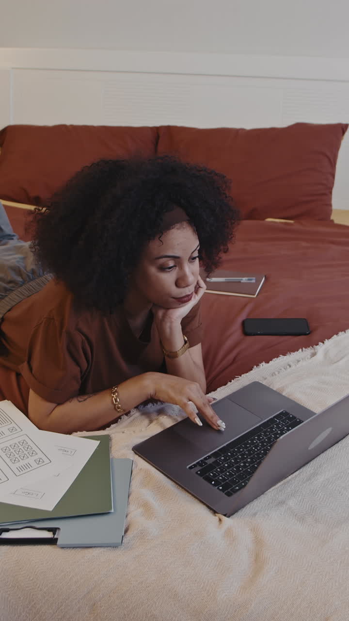 Female Graphic Designer Working on Laptop on Bed