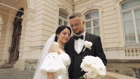 Newlyweds-portrait,-caucasian-groom-bride-walking,-embracing,-hugs-near-old-castle,-wedding-couple