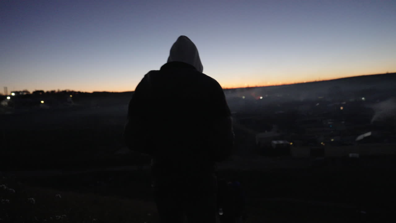 Person Silhouetted at Sunset Over a Cityscape