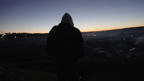 person silhouetted at sunset over a cityscape