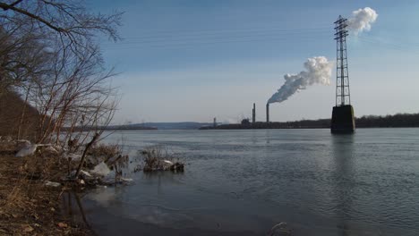 smoke rises from a distant power plant along a river