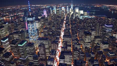 breathtaking aerial view of new york city skyline illuminating at night, featuring prominent skyscrapers, car lights trails, and the hudson river in the background