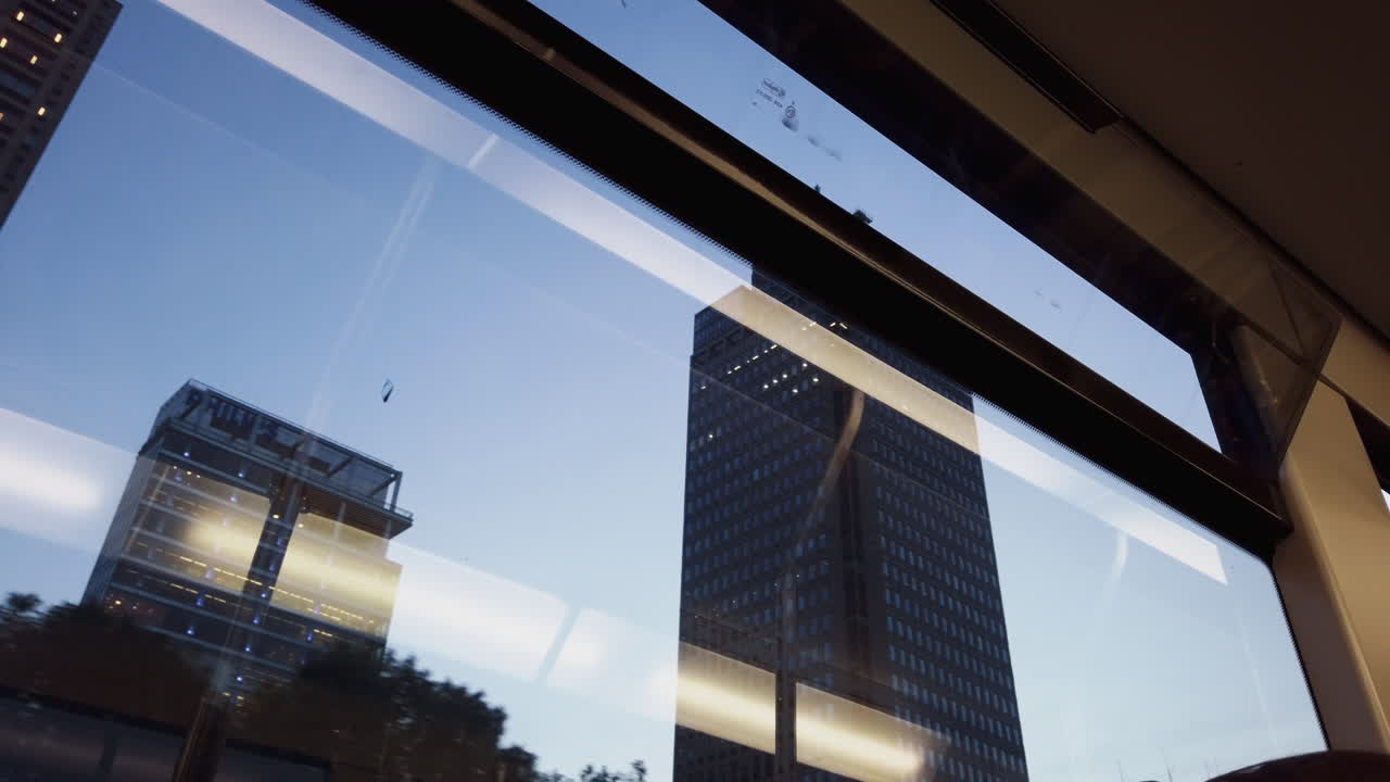 저녁 빛 속에서 건물이 지나갈 때 지상을 여행하면서 지하철 창밖을 내다본다