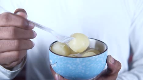 persona comiendo rasgulla: una vista de cerca de un delicioso postre indio
