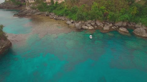 pull back aerial view on solitary boat anchored in tropical lagoon of exotic island