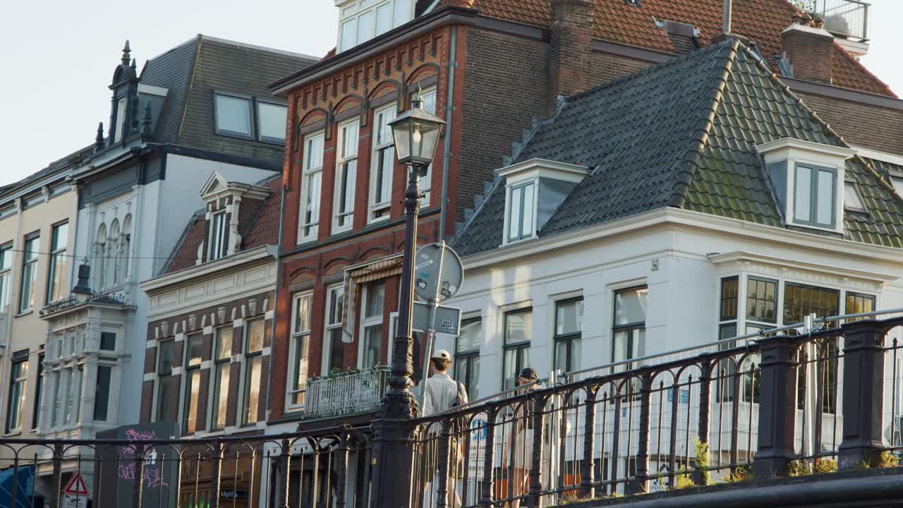 Pedestrians cross a Dutch bascule bridge beside historic canal buildings in Haarlem, Netherlands