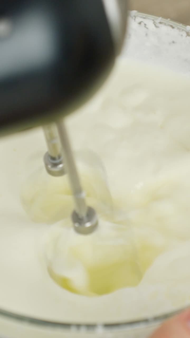 Electric whisk beating white cream mixture for tiramisu dessert recipe, vertical