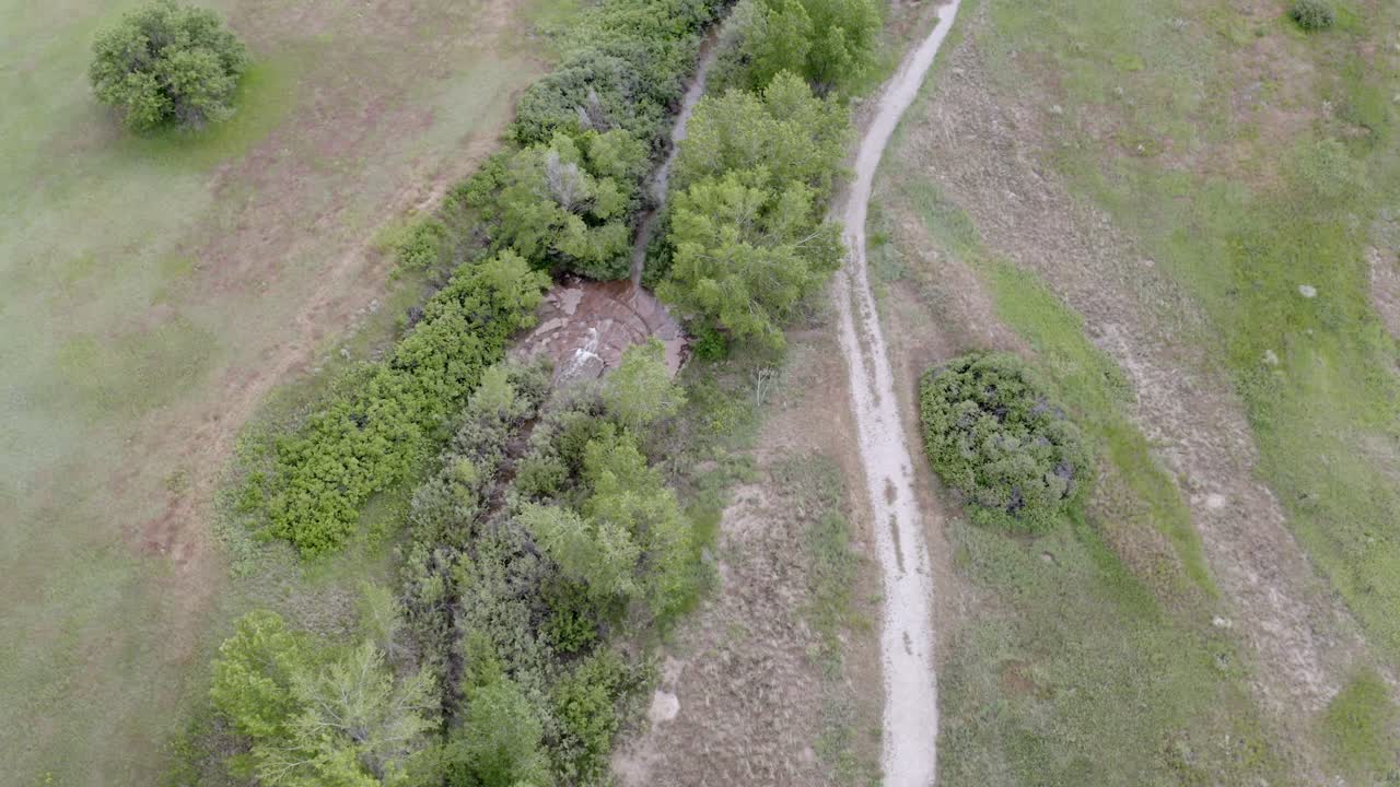 vista aérea sobre un pequeño arroyo con una pequeña cascada en medio de un gran campo de espacio abierto