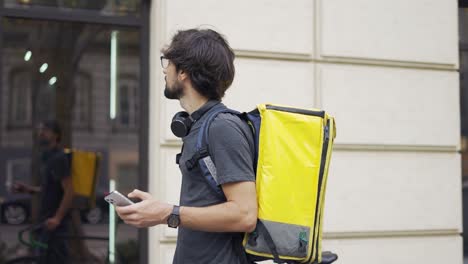 el hombre de la entrega que está yendo y enviando mensajes de texto en el teléfono inteligente, buscando la ruta