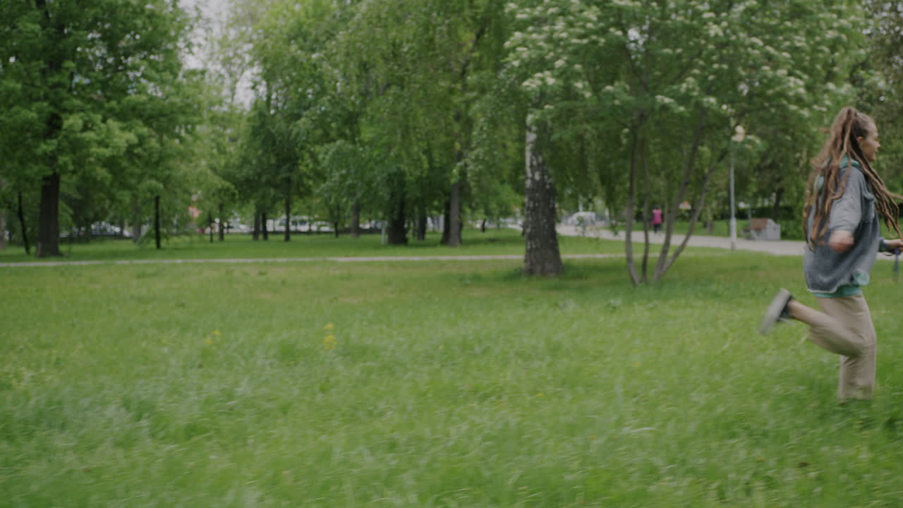Woman with dreadlocks walking her dog in the park
