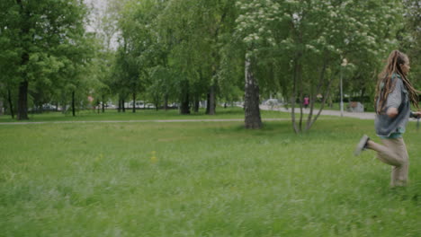 woman with dreadlocks walking her dog in the park
