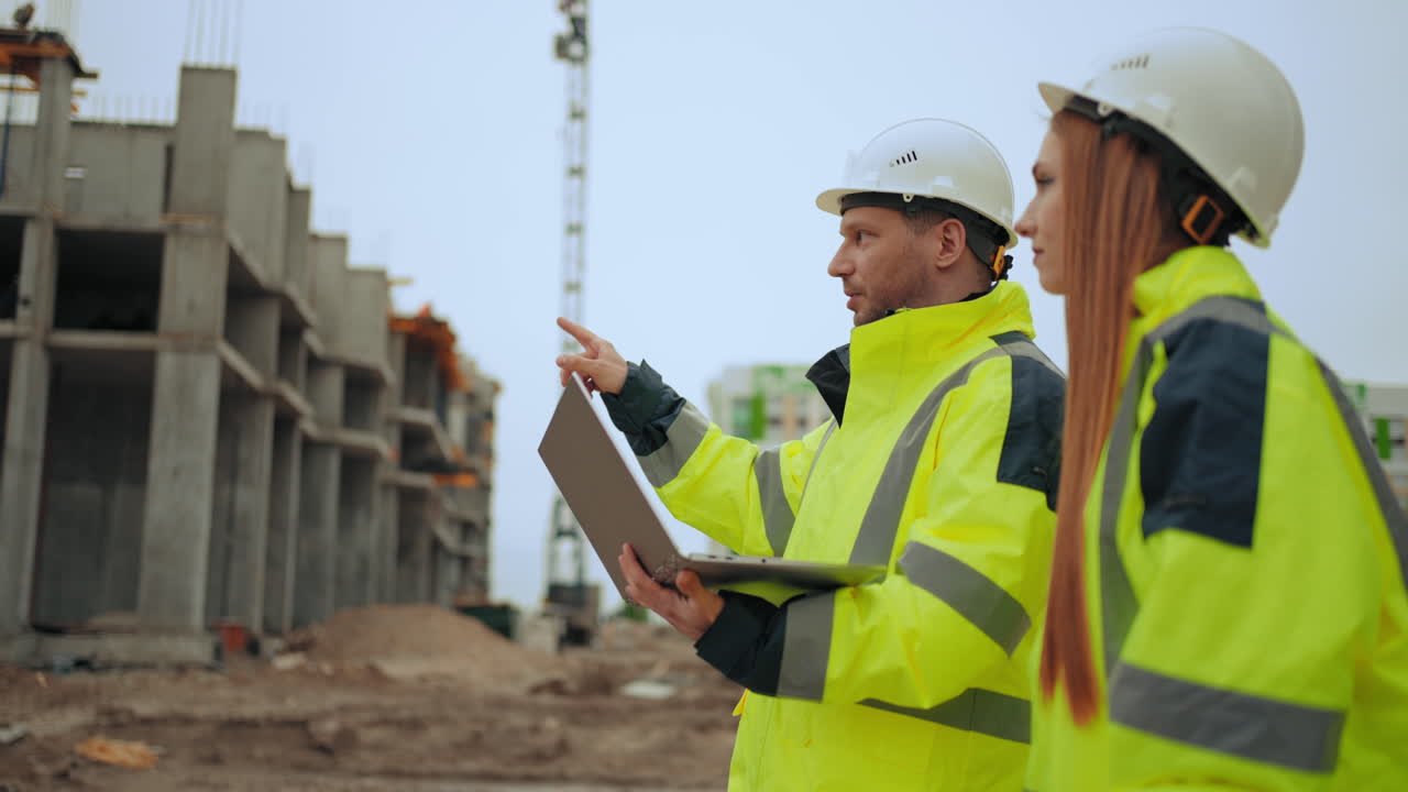 los ingenieros civiles están inspeccionando el sitio de construcción el capataz masculino y la arquitecta están caminando por el área de construcción