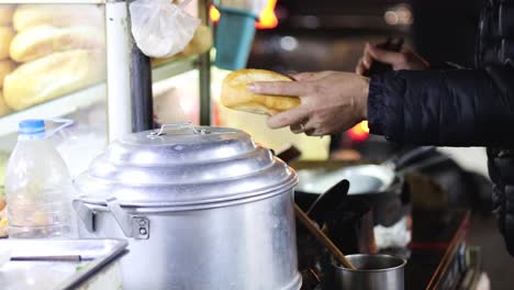 vendor serves banh mi sandwiches to customers at night