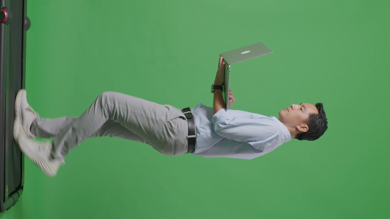 사이드 뷰 아시아 사업가의 전체 몸은 스튜디오에서 녹색 화면 배경에서 는 동안 노트북 컴퓨터를 사용합니다.