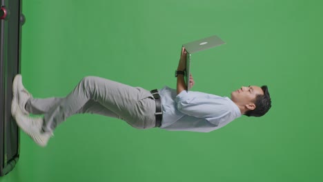 사이드 뷰 아시아 사업가의 전체 몸은 스튜디오에서 녹색 화면 배경에서 는 동안 노트북 컴퓨터를 사용합니다.