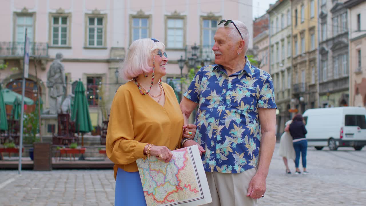Senior couple grandmother and grandfather tourists talking having conversation on street in old city