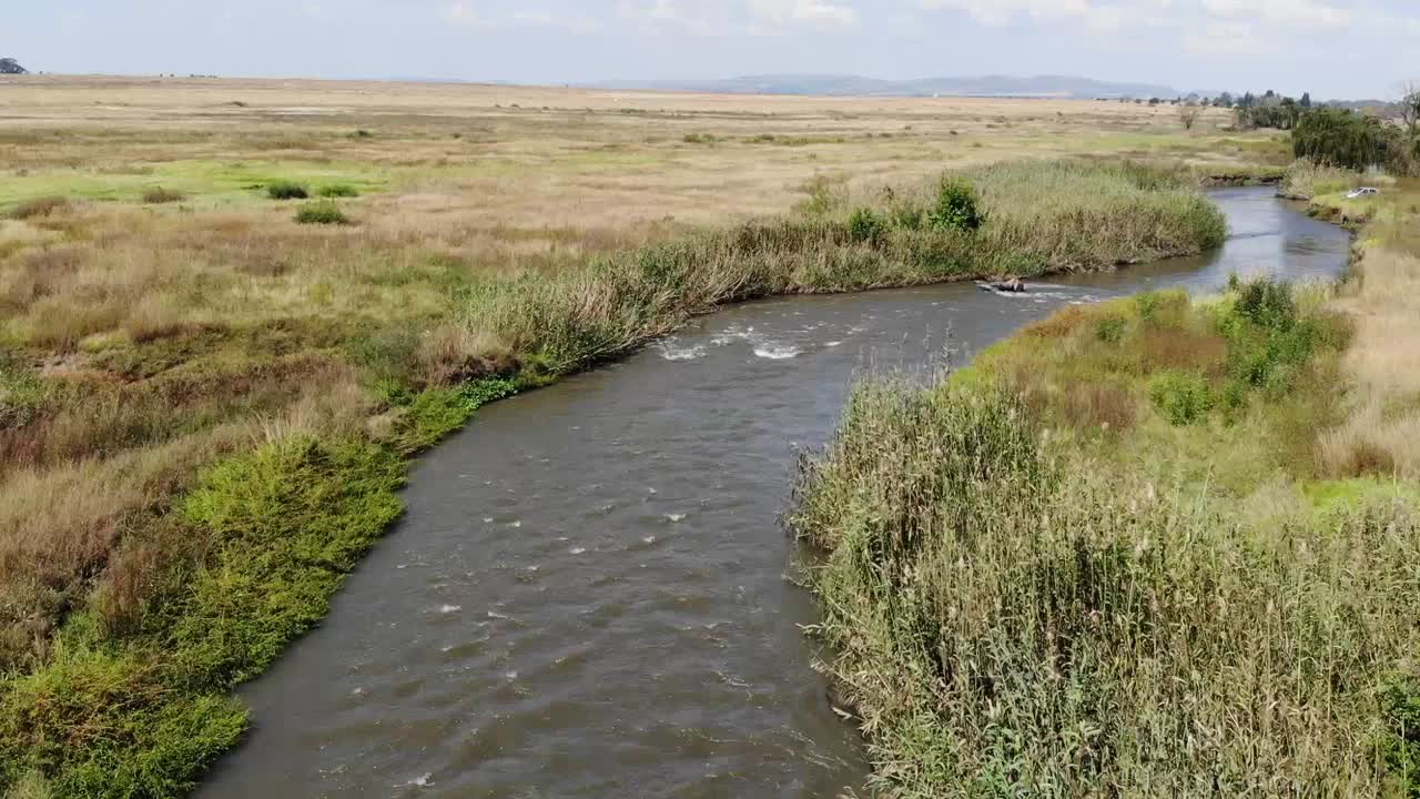 Ripresa aerea con drone del fiume che scorre sotto un ponte di strada sterrata remoto a Johannesburg, Sudafrica