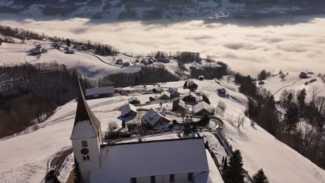 Church on the hill of Weesen. Aerial view of the shores of Lake Walensee covered in thick fog at sunrise. Drone shot