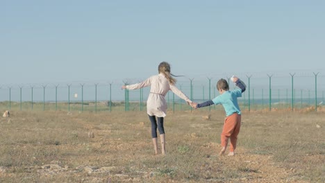 niños hermano y hermana de oriente medio están en un campamento de refugiados resultado del conflicto de guerra. niños pobres sin zapatos, van descalzos por un camino de tierra a la valla