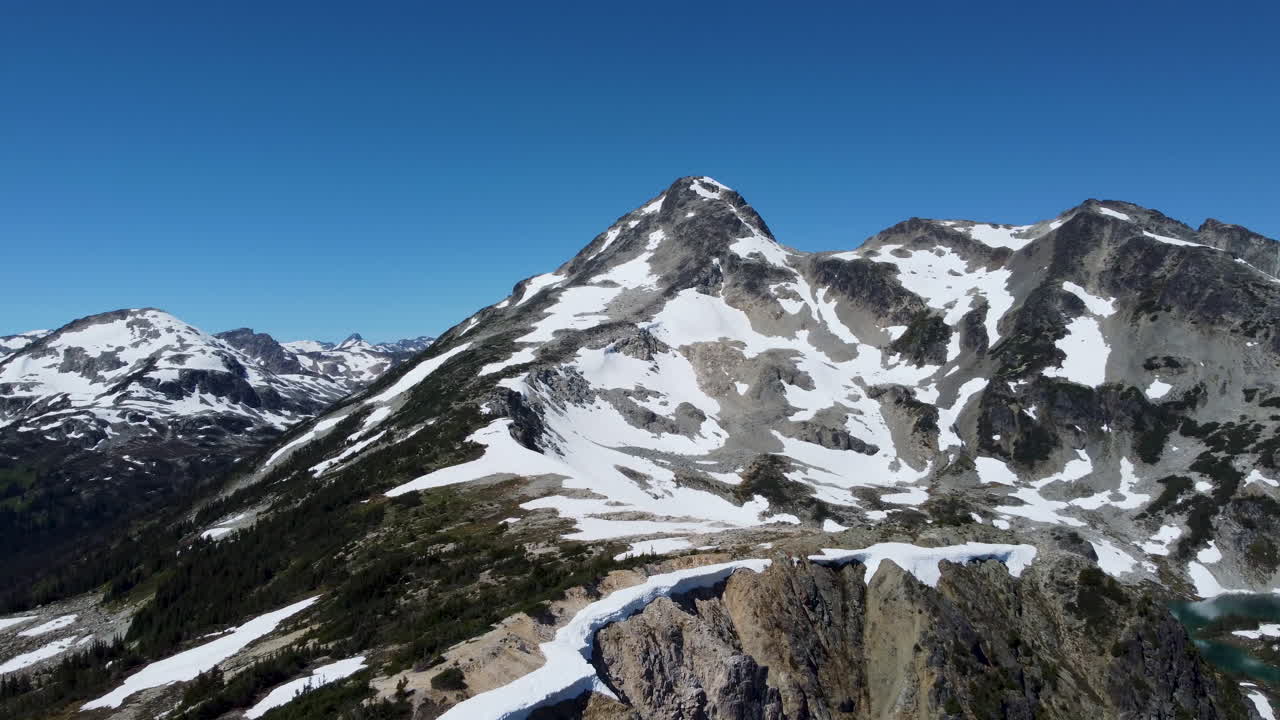 캐나다 bc 4k의 태평양 지역에 눈 소나무와 밝은 푸른 하늘이 있는 슈거로프 산 - 옆으로 드론 공중 촬영