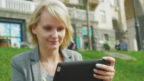 Young-Woman-Resting-In-The-Park-Enjoys-A-Digital-Tablet-4k-Video