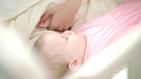 niña pequeña durmiendo en la cama. la mano de la madre acariciando al niño dormido