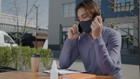 man working outdoors in cafe wearing mask