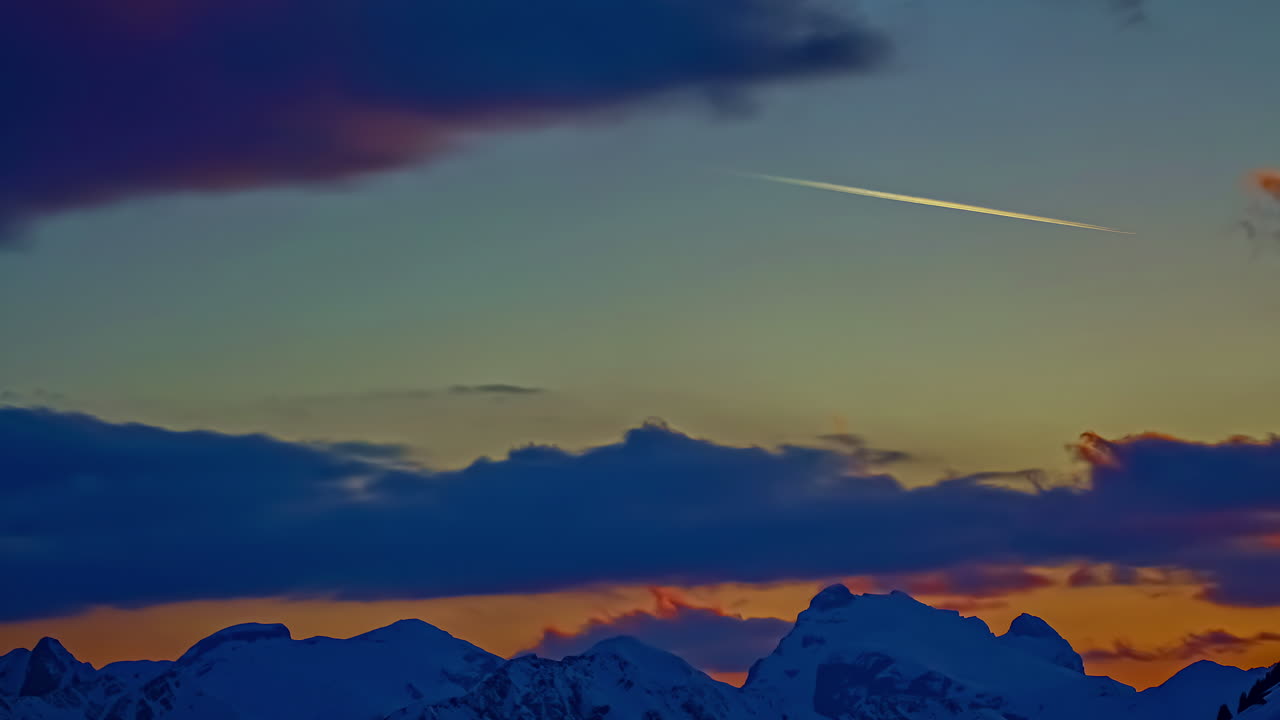 toma de lapso de tiempo de nubes oscuras que emergen en el cielo sobre montañas nevadas en invierno al atardecer