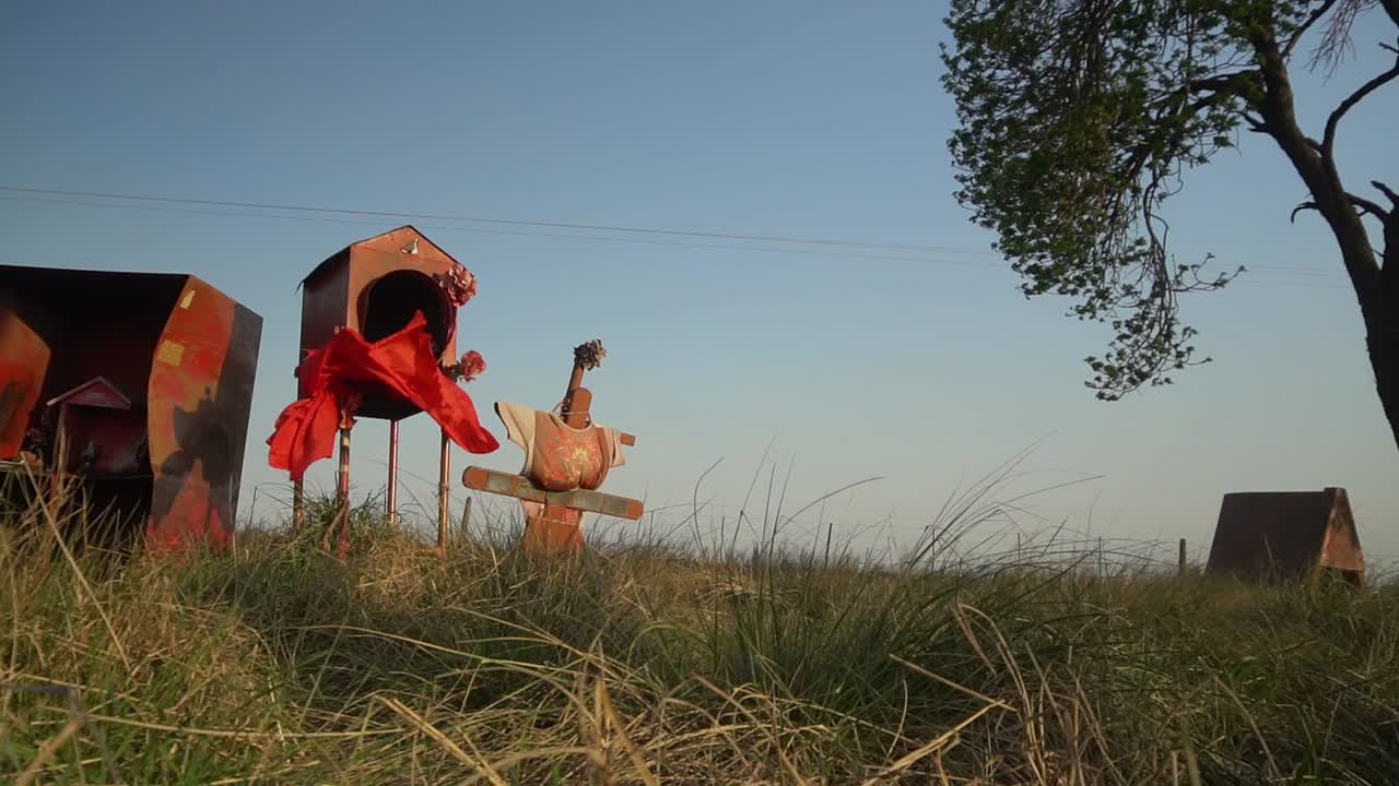 Slow-motion, wide panning view of a roadside shrine honoring popular saint Gauchito Gil