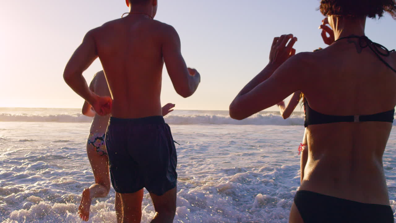 해가 지면 파도 속에서 달리는 친구들