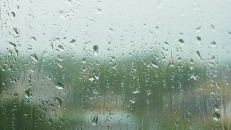 Gotas-De-Lluvia-Deslizándose-Lentamente-Sobre-El-Cristal-De-La-Ventana-En-Un-Día-Lluvioso,-Toma-De-Primer-Plano-Medio