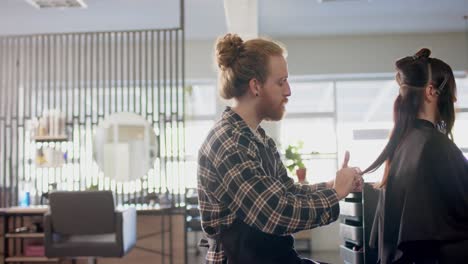 Caucasian-male-hairdresser-cutting-ends-of-client's-long-hair-with-scissors-at-salon,-in-slow-motion