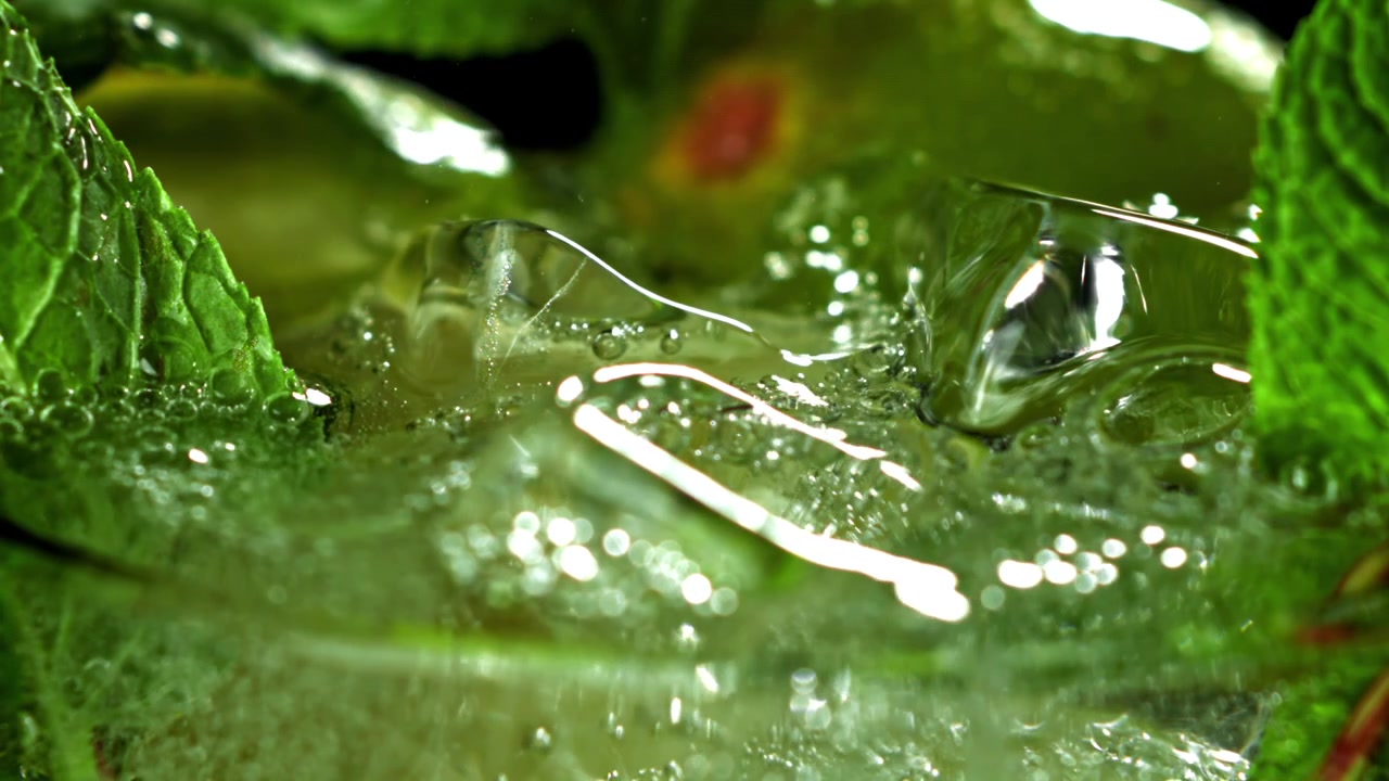 Macro di cubetti di ghiaccio e foglie di menta che frizzano in una bevanda verde