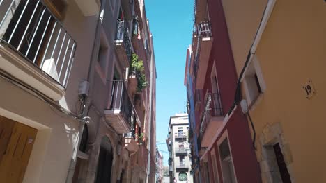 narrow sunlit alley in tarragona, spain, with historic buildings and a clear blue sky