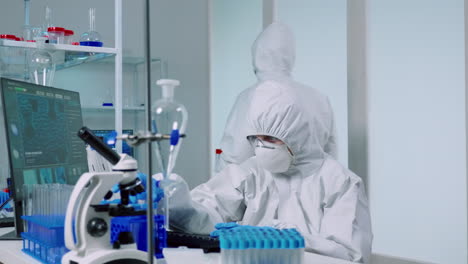 ccientist with coverall in lab performs tests with blue liquid