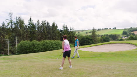 Female golf players playing golf and knocking golf ball out on golf course