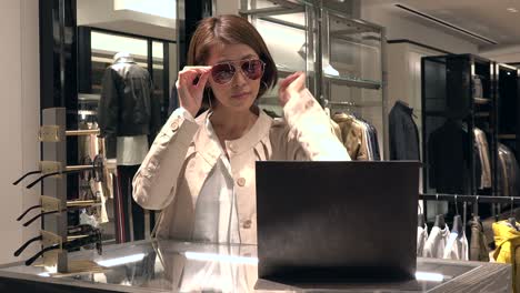 attractive lady trying and wearing sunglasses in fashion shop