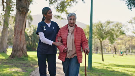 nurse assisting elderly woman with walking in a park