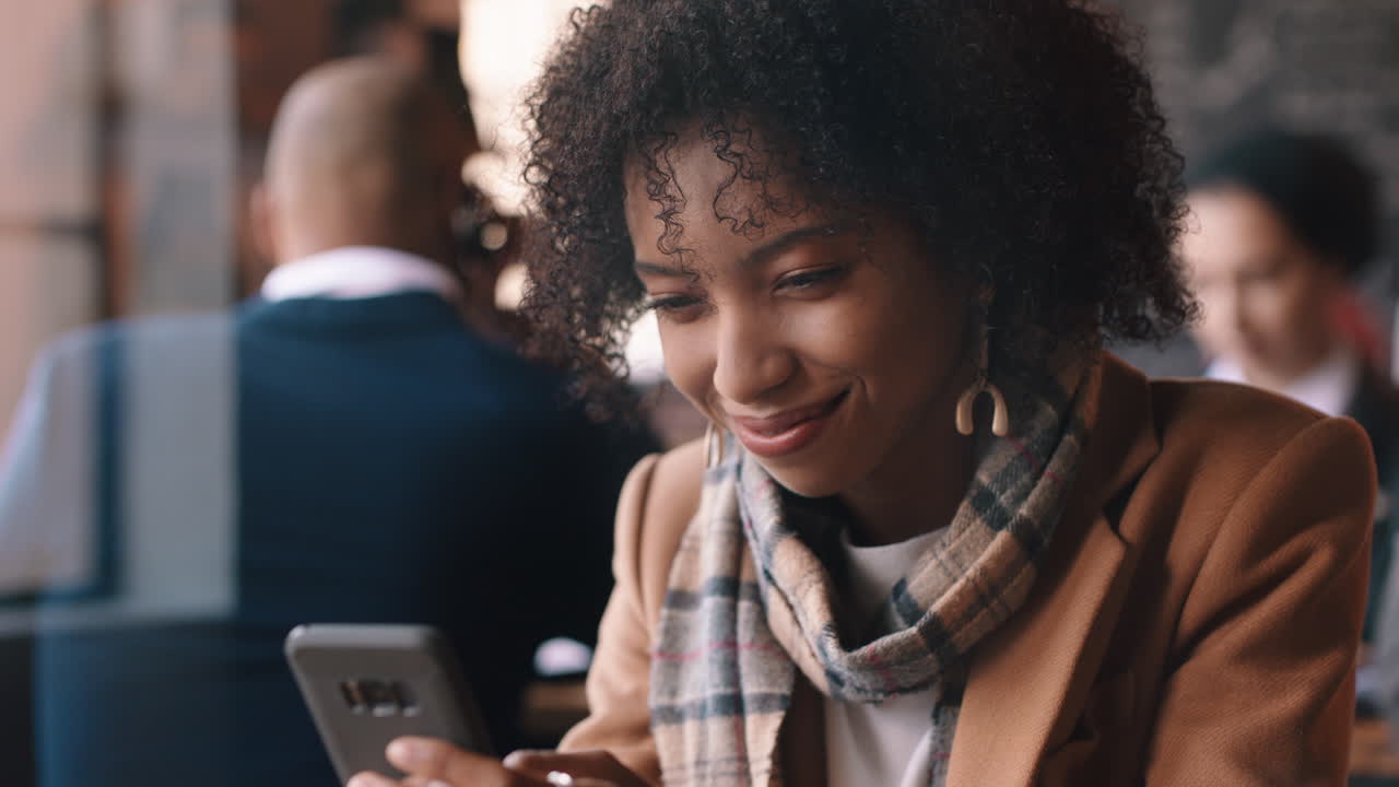 beautiful african american woman using smartphone in cafe texting sharing messages on social media enjoying mobile technology in busy restaurant
