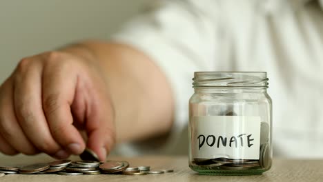 a  money coins falling into the glass jar with label of donate text , business and financial of  money saving concept , 4k dci resolution