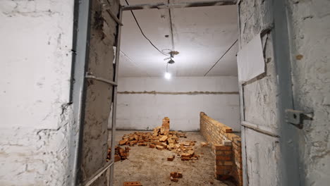 light bulb hanging from the ceiling illuminating the large room. brick wall is added in the middle of the room. tour around the building with old walls.