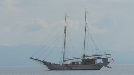 A-traditional-schooner-gently-floats-near-Kir-Island,-Raja-Ampat,-Indonesia