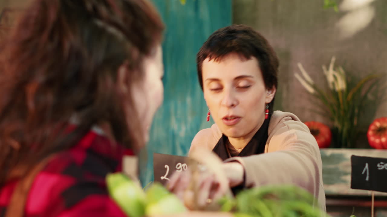 A woman hands over a grocery bag at a produce stand
