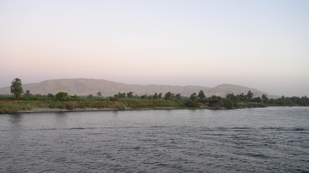 Sunset on the Nile River, mountain in the background with the serene farmland on the banks of the Nile River in the foreground