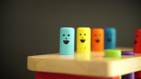 una foto de juguetes de madera para niños de diferentes colores con caras sonrientes en ellos