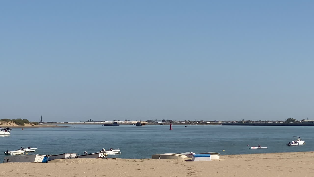 Fishing boats float gently on calm blue waters under the warm Andalusian sun in Sanlúcar de Barrameda